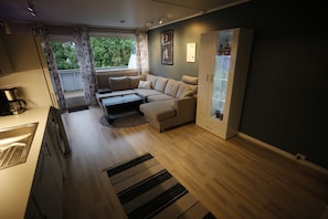 Ein modernes Wohnzimmer mit einer Couch, einem Couchtisch, einem Schrank und einem Fenster mit Vorhängen.