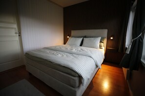 Ein Schlafzimmer mit einem Bett, einem Nachttisch, einer Lampe und einer Tür.
