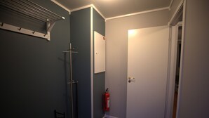 Ett badrum med dusch, handduksställ och brandsläckare.