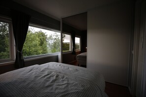 A bedroom with a bed, a window, and a view of trees. - Cozy two-story apartment with a sauna (Tromsø)
