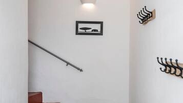 A staircase with a checkered floor, a wooden bench, and a wall-mounted light fixture.