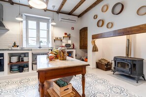 Una cocina con una mesa de madera, una estufa y varios utensilios de cocina.