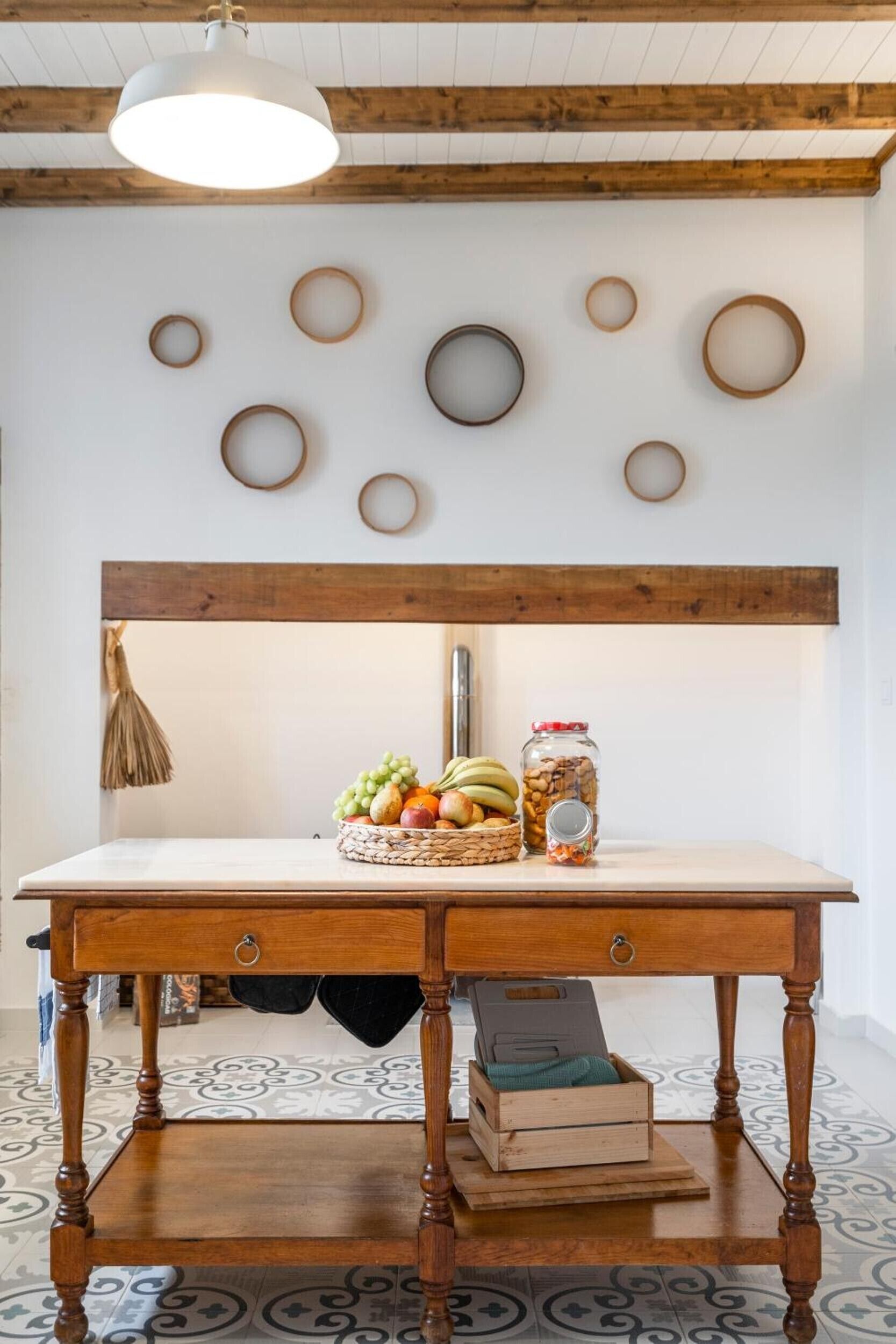 A wooden table with a woven basket of fruit, a jar of nuts, and a metal container.