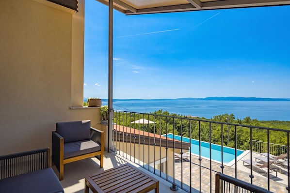 Un balcon avec vue sur la mer, une piscine et un espace salon.