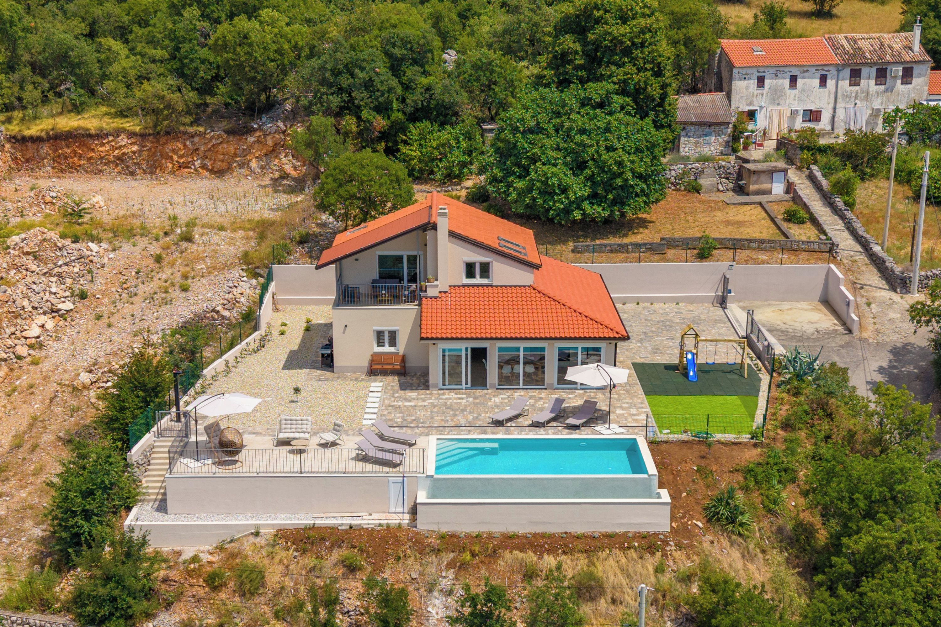 A two-story house with a swimming pool, outdoor seating, and a garden.