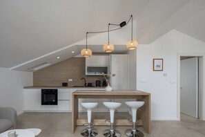 Eine moderne Küche mit Essbereich, inklusive einem Holztisch und drei weißen Barhocker.