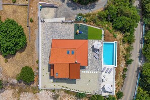 Eine Luftaufnahme eines Anwesens mit Schwimmbad, überdachter Terrasse und umzäunter Garten.