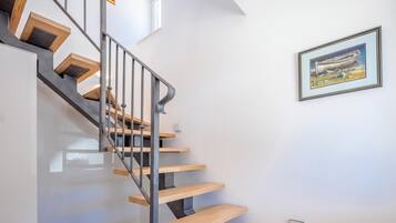 A modern staircase with wooden steps and metal railings, leading to a landing with a framed artwork.