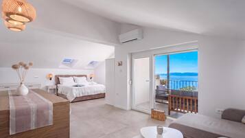A modern bedroom with a bed, bedside table, and a view of the sea through a balcony.
