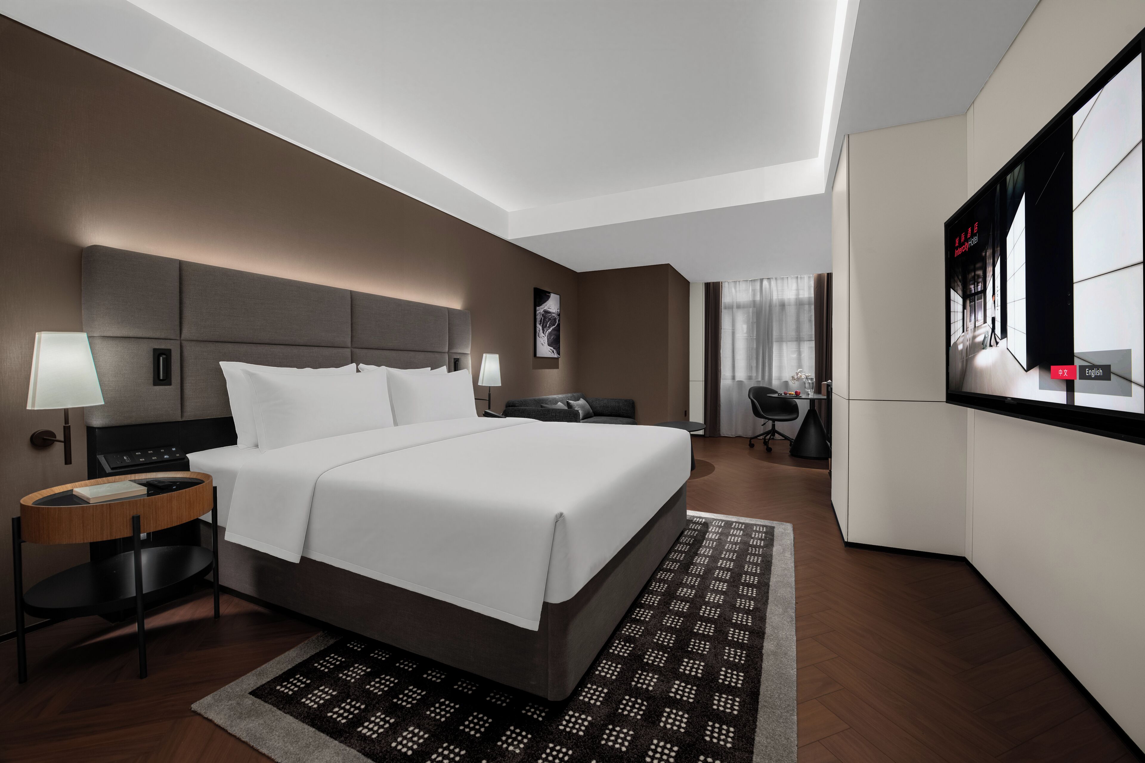 Una habitación de hotel moderna con una cama grande, mesitas de noche, un escritorio y un área de estar.