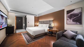 A modern hotel room with a large bed, a desk, a chair, and a television.