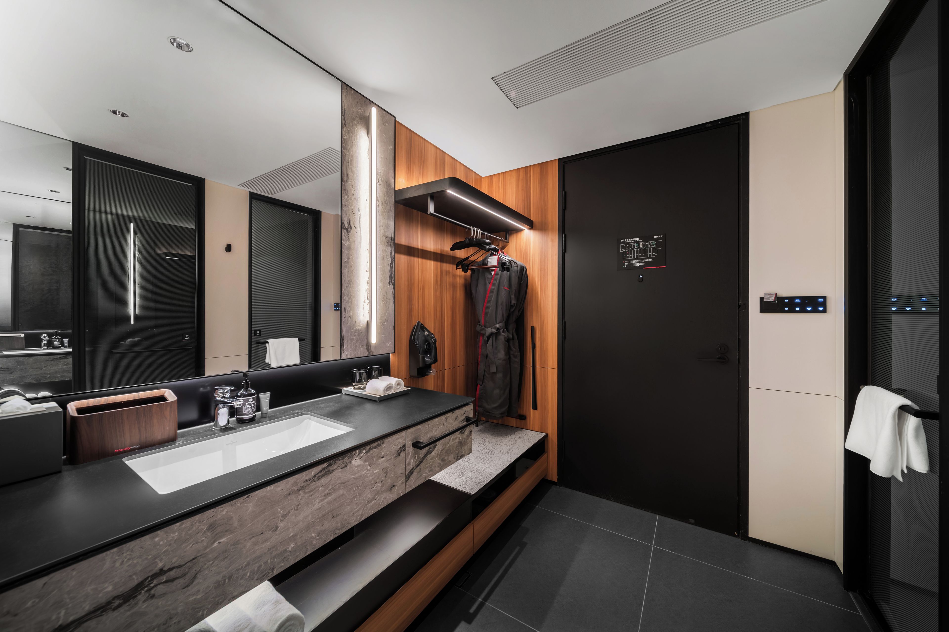 A modern bathroom with a dual sink vanity, a mirror, a towel rack, and a shower area.
