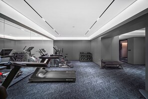 A modern gym with various exercise equipment, a bench, and a small table. - Shanghai Intercity Expo Center Hotel (Shanghai)