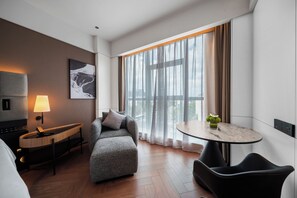 Una habitación de hotel moderna con un sofá, una mesita con una planta, una lámpara y un cuadro en la pared.