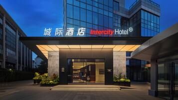 Ein moderner Hotel Eingang mit Glasfassade und beleuchteter Beschilderung.
