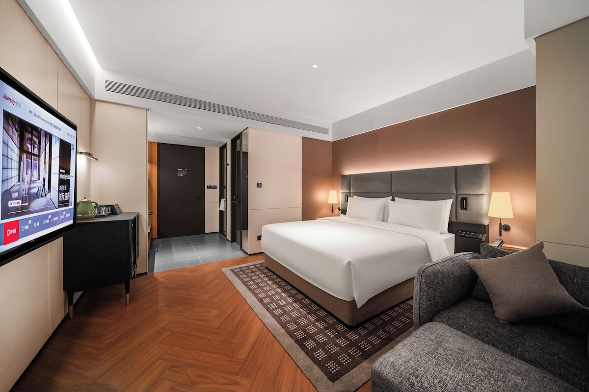 A hotel room with a bed, a sofa, a TV, and a bathroom.