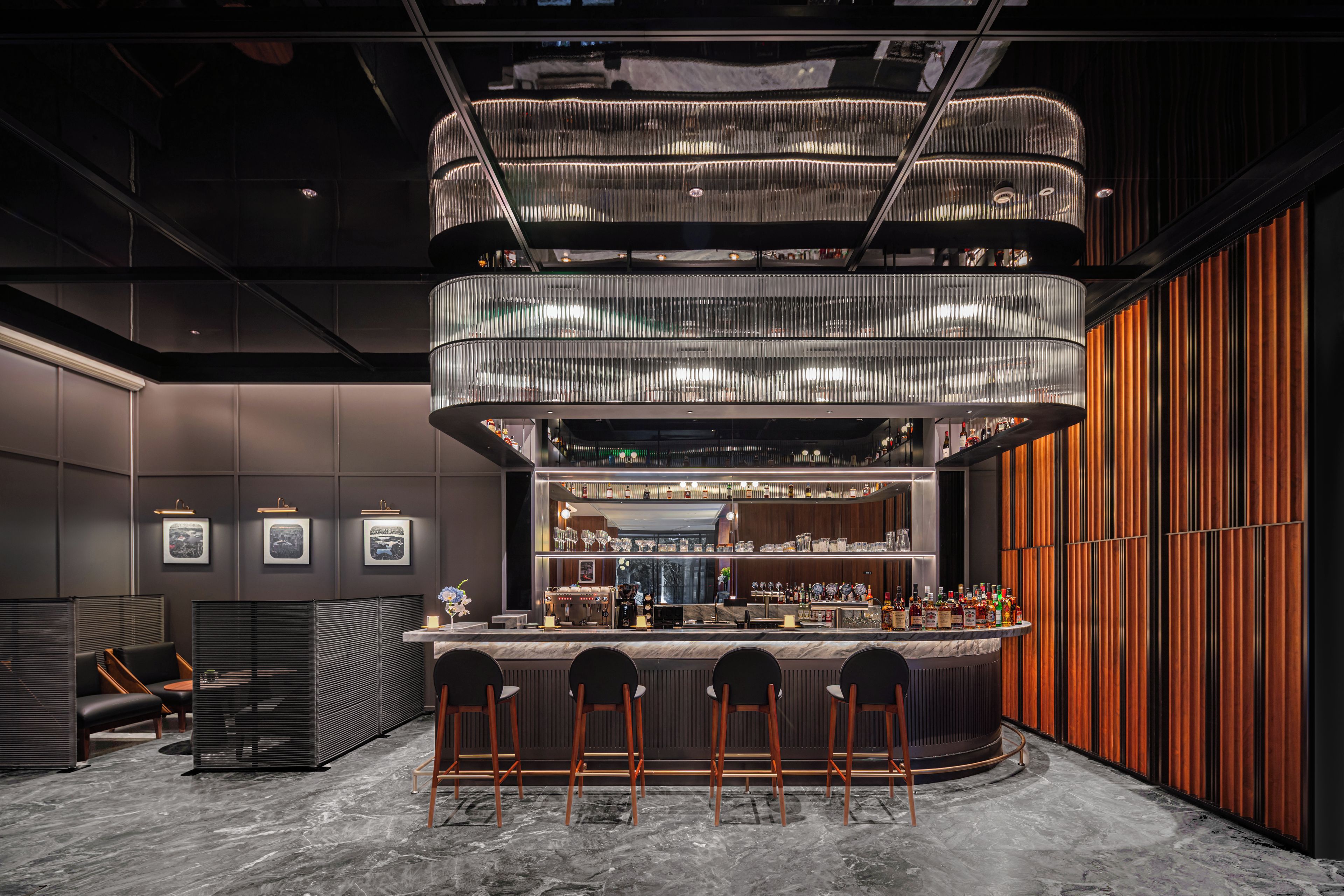 A modern bar area with a central bar counter, multiple seating options, and a distinctive ceiling design.