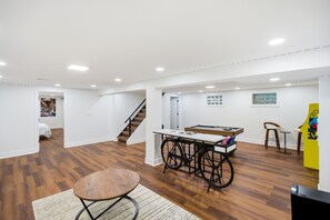A spacious room with a wooden floor, a pool table, a bicycle, and a staircase leading to another area. - Spacious 4-bedroom house in adorable Cincinnati close to downtown (Cincinnati)