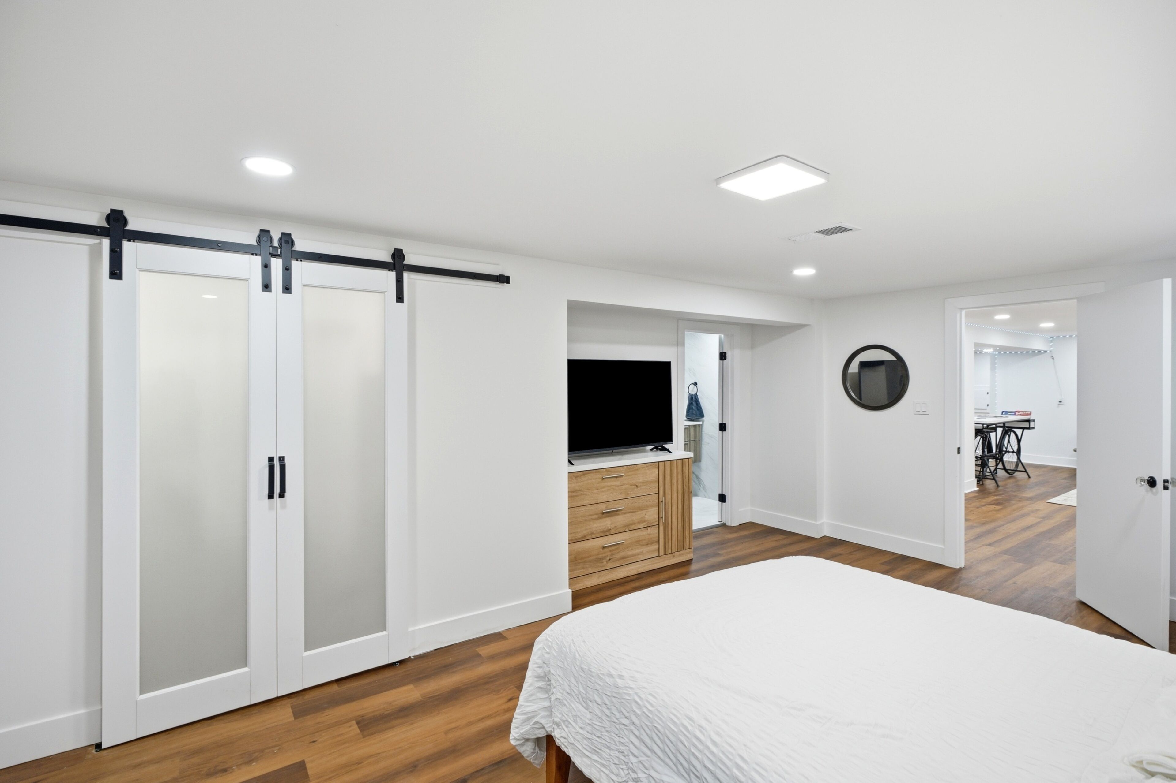 Un dormitorio con cama, armario, televisión y espejo circular.