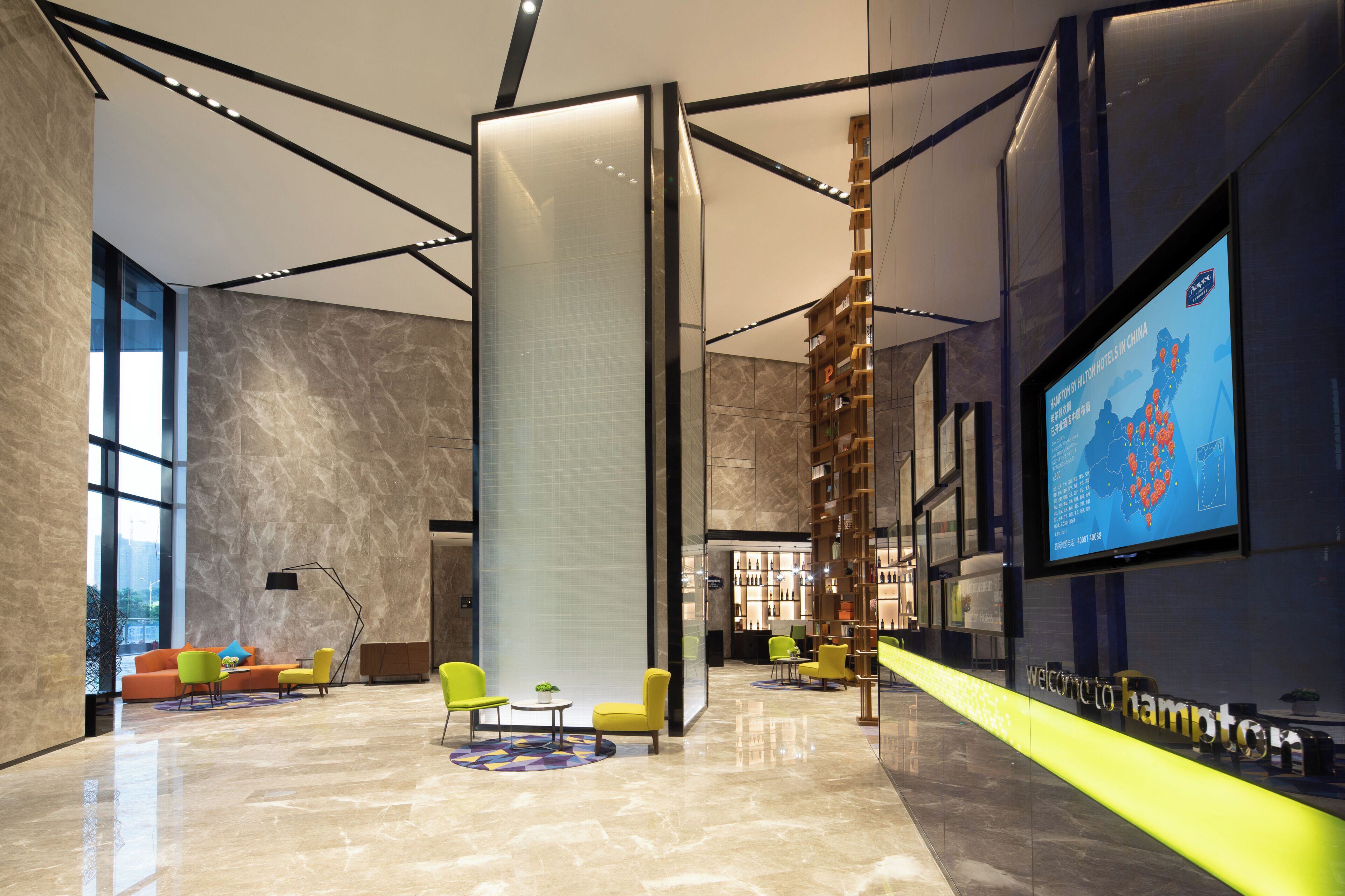 A modern lobby with a large digital screen, seating areas, and a reception desk.