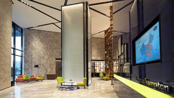 A modern lobby with a large digital screen, seating areas, and a reception desk.