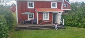 A red house with a porch, a table, and chairs.