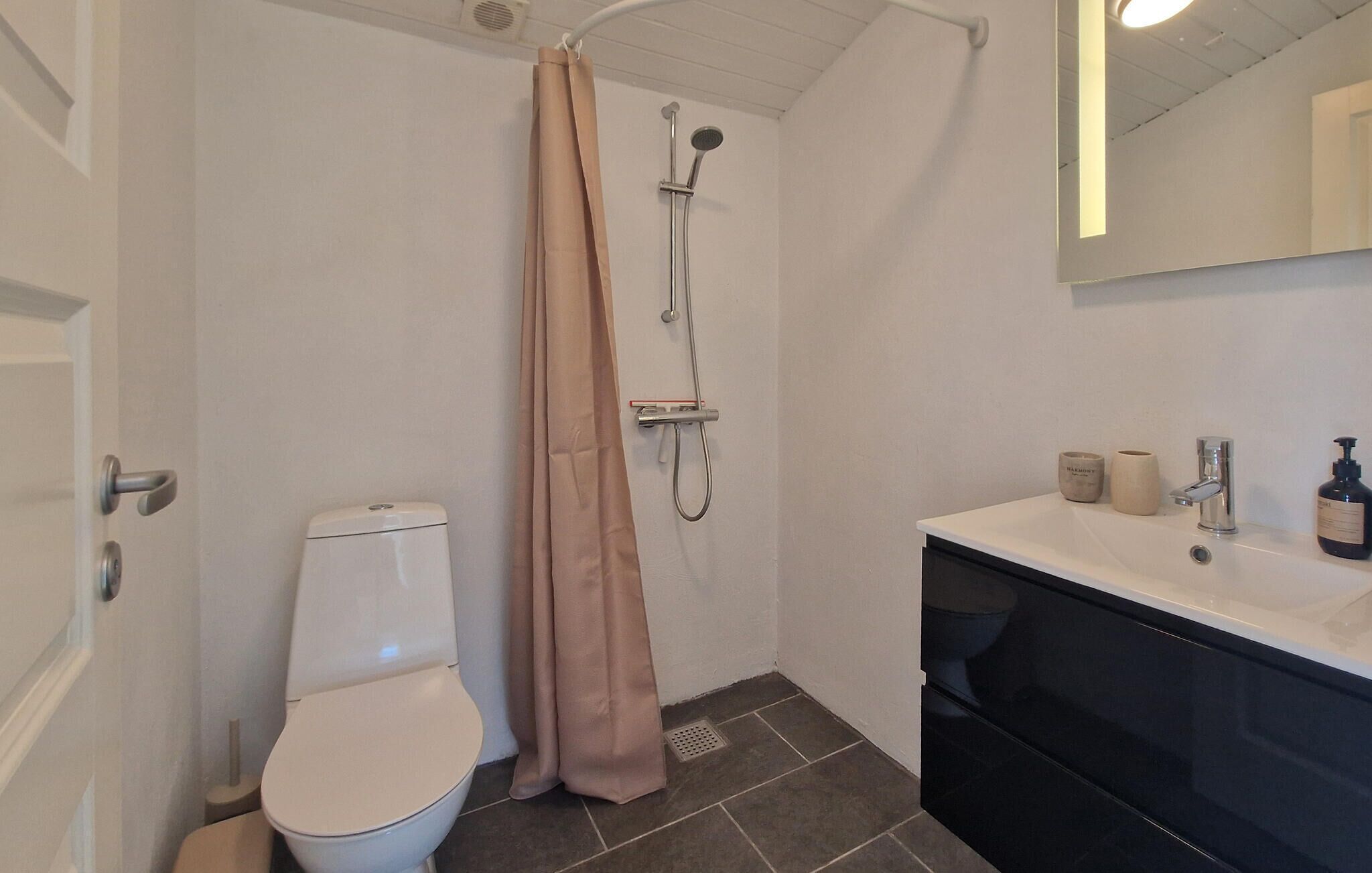 Une salle de bain équipée de toilettes, d’une douche, d’un lavabo et d’un miroir.