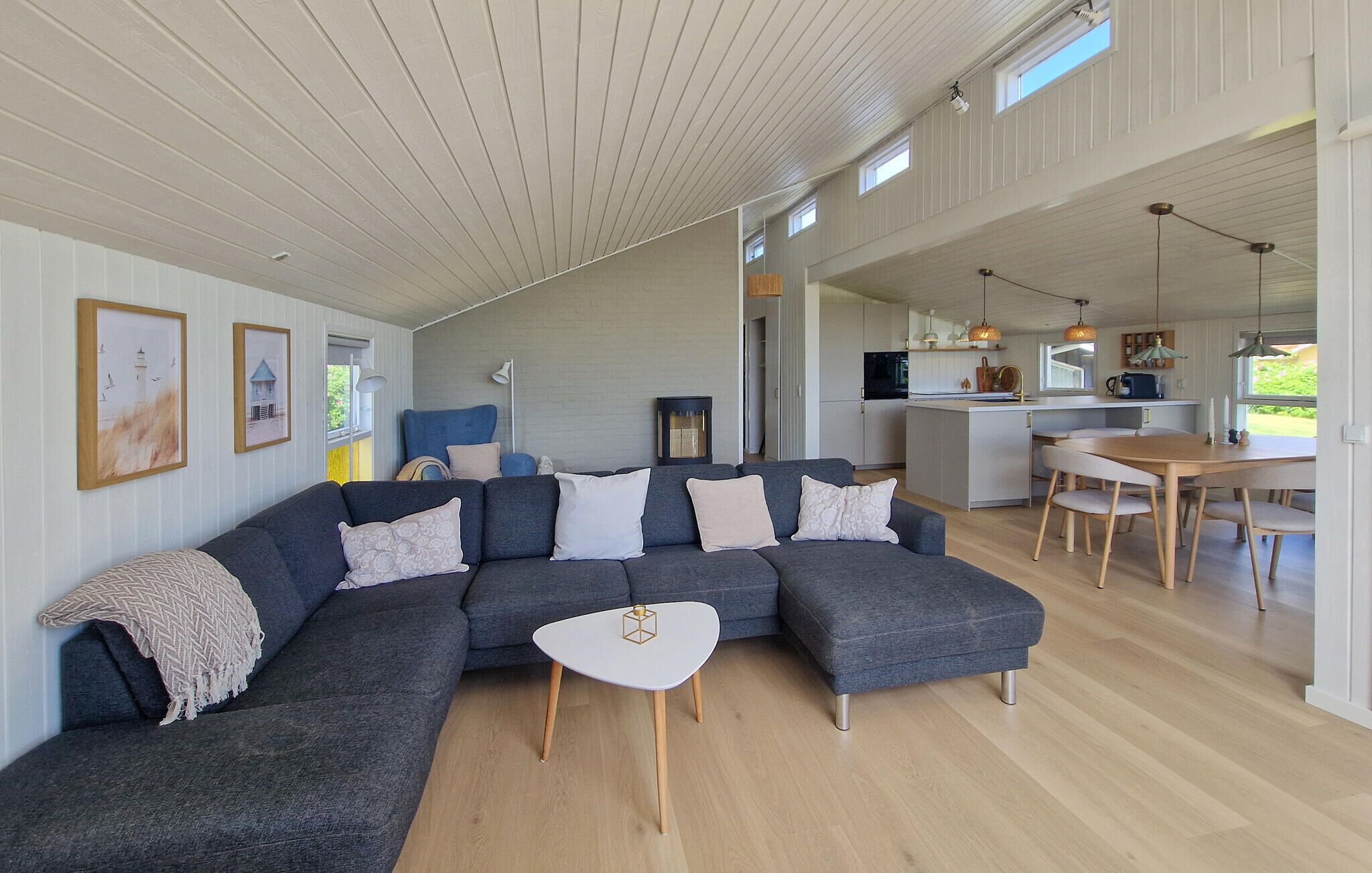 Ein modernes Wohnzimmer mit Ecksofa, einem Esstisch und einem durch einen offenen Raum einsehbaren Küchenbereich.