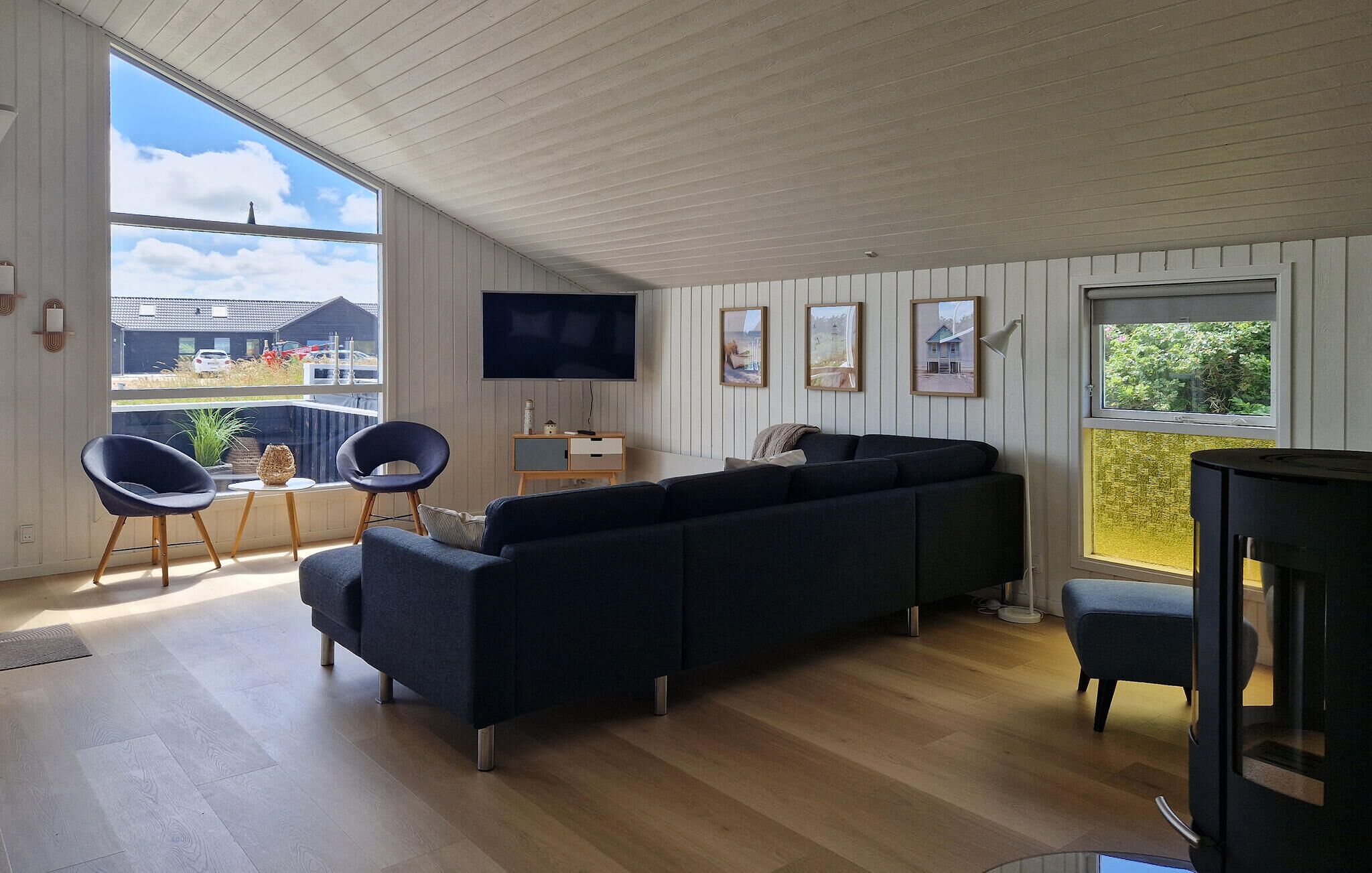 A modern living room with a sectional sofa, a flat-screen TV, and a dining area with chairs.