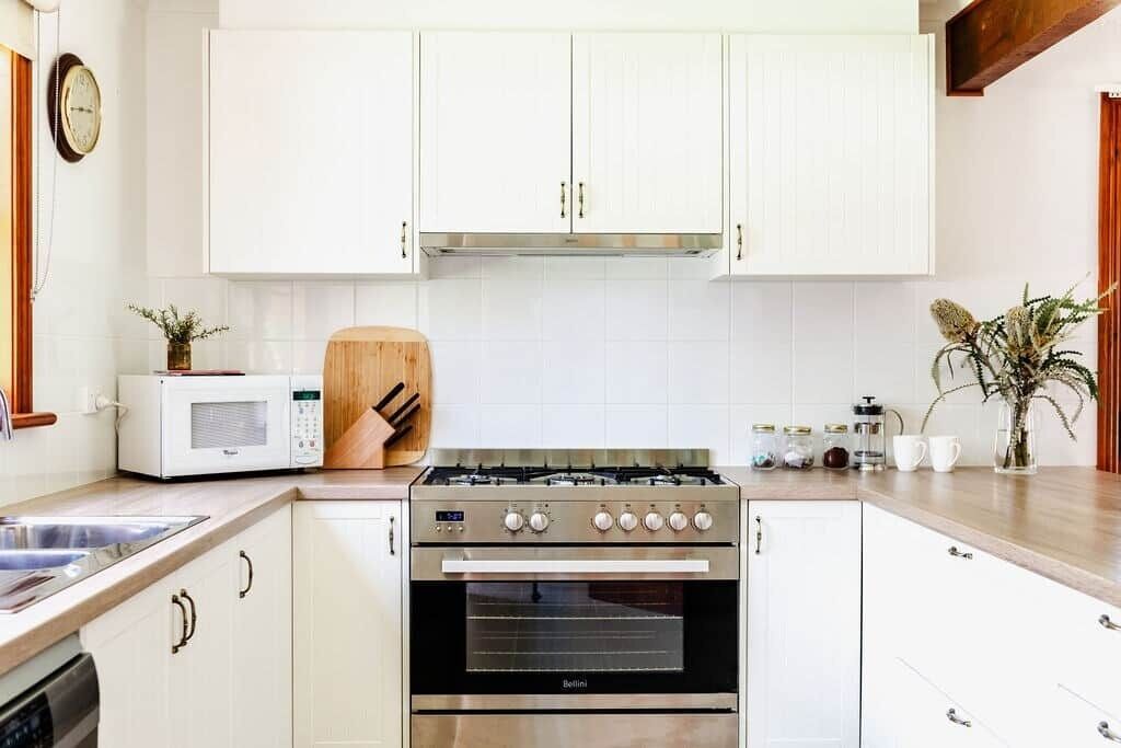 A kitchen with white cabinets, a stove, a microwave, and a dishwasher.