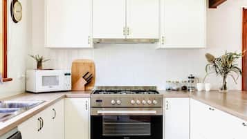 A kitchen with white cabinets, a stove, a microwave, and a dishwasher.