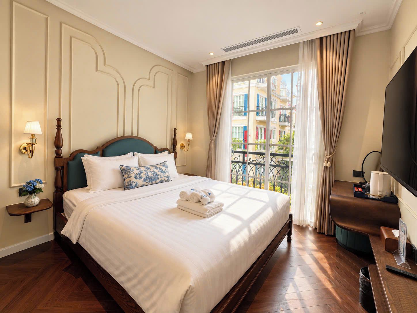 Una habitación de hotel con una cama grande, televisión y un balcón con vistas a edificios.