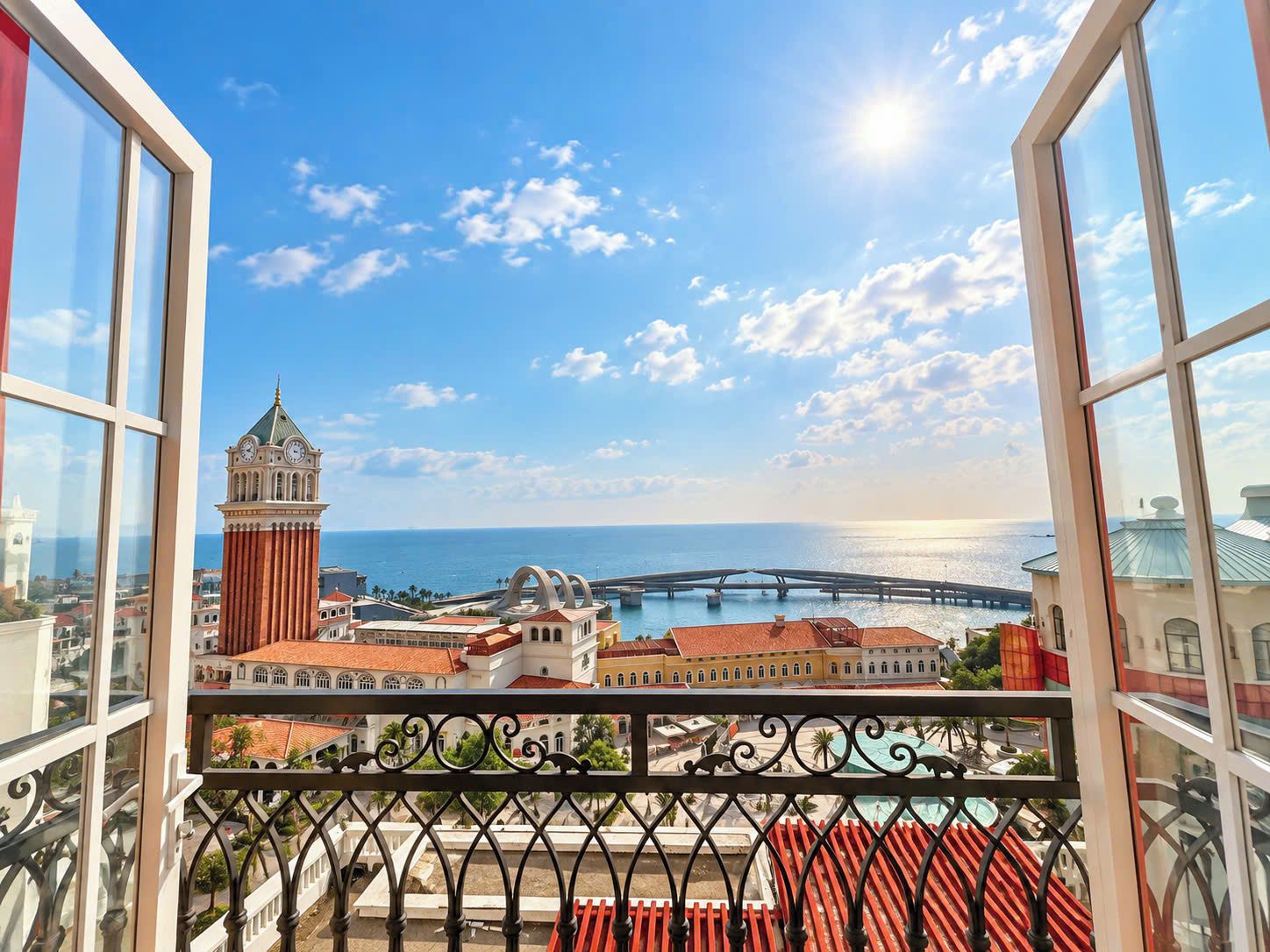 A balcony with a view of a coastal cityscape, including a prominent clock tower and a bridge.