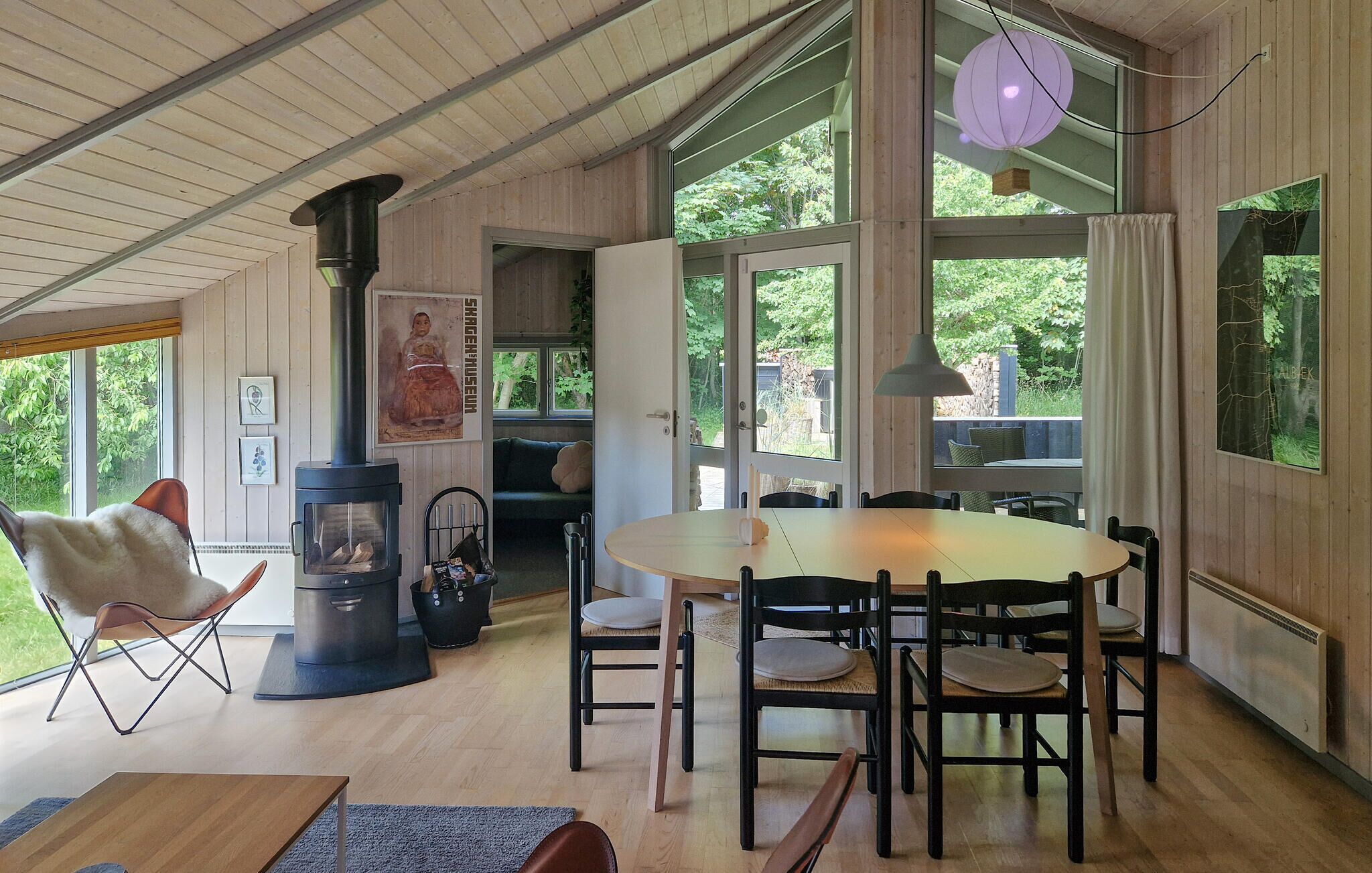 A cozy room with a round table, chairs, a fireplace, and large windows.