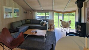 A cozy living room with a sofa, a coffee table, a fireplace, and a view of the outdoors. - Nice home in ålbæk with sauna (Ålbæk)