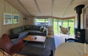 Ein gemütliches Wohnzimmer mit Sofa, Couchtisch, Kamin und Blick ins Freie.