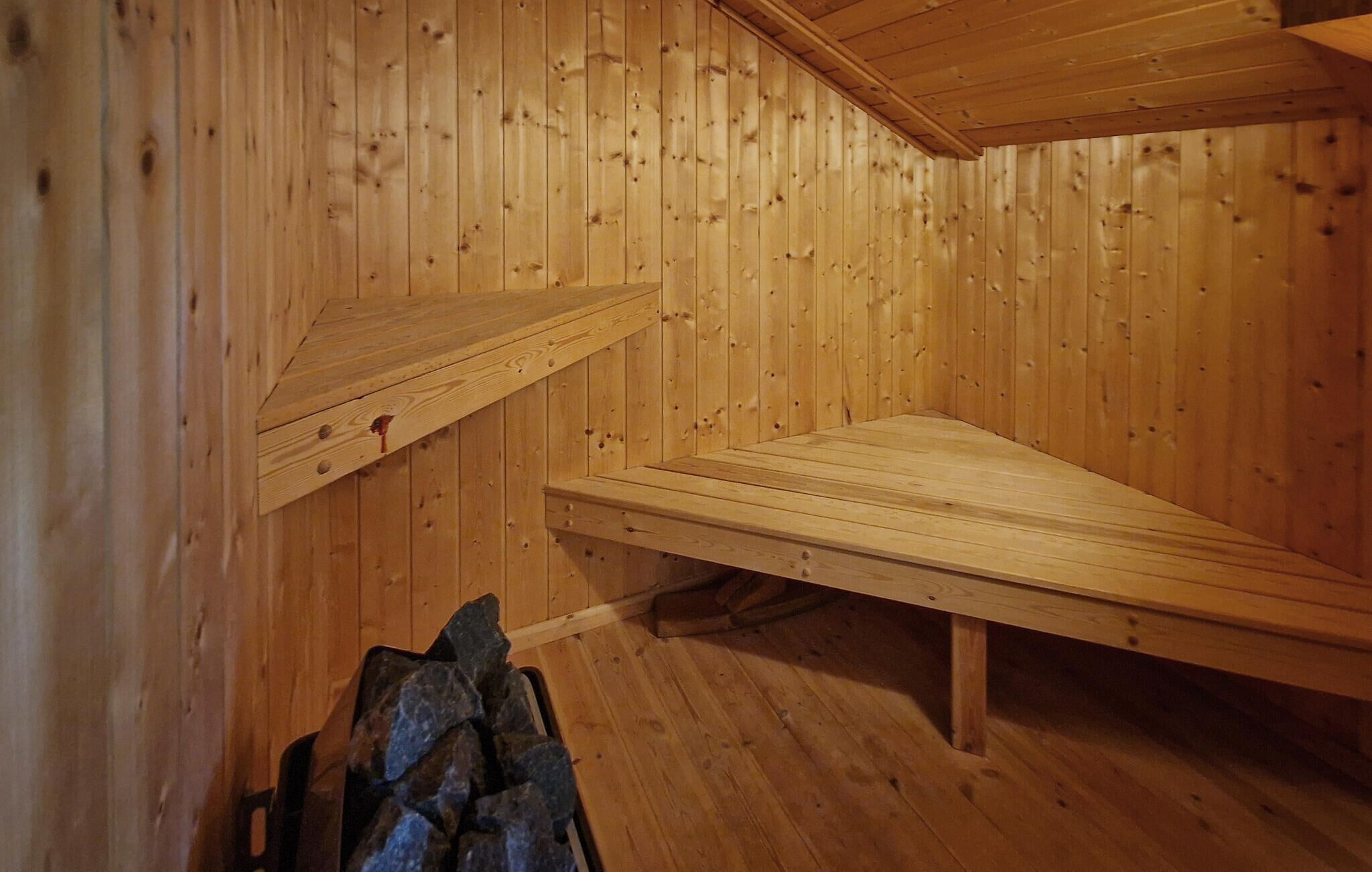 Un sauna en bois, doté de bancs et d ’un récipient en pierre.