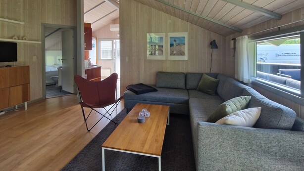 A modern living room with a sofa, a coffee table, and a red chair. - Nice home in ålbæk with sauna (Ålbæk)