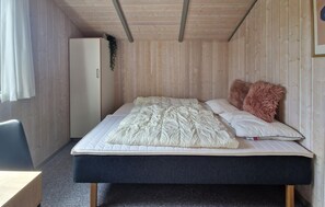 Ein kleines Zimmer mit Bett, Schreibtisch und Kleiderschrank.