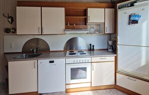 Eine kleine Küche mit Geschirrspüler, Herd, Backofen und Kühlschrank.