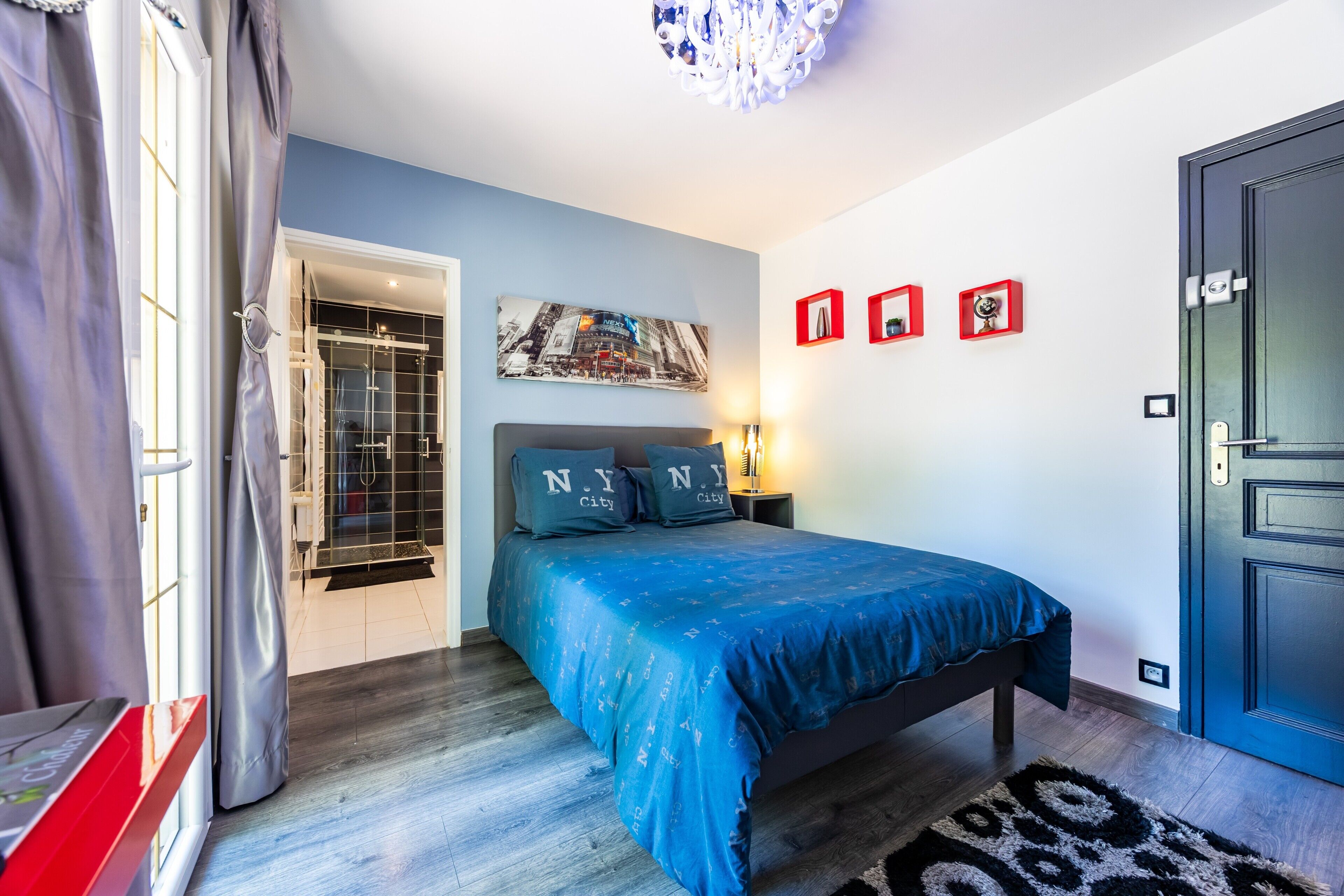 A bedroom with a bed, a nightstand, a wall-mounted picture, and a door.