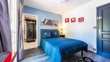 A bedroom with a bed, a nightstand, a wall-mounted picture, and a door.