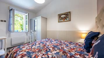 A bedroom with a bed, a window, a radiator, and a wall-mounted picture.