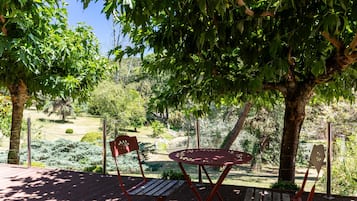 A wooden deck with a table and chairs, surrounded by trees and a garden.