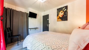 A bedroom with a bed, a chair, a TV mounted on the wall, and a door.
