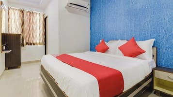 A hotel room with a bed, a nightstand, a wardrobe, and an air conditioning unit.