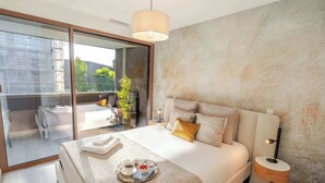 A modern hotel room with a large bed, a glass door leading to a balcony, a bedside table with a lamp, and a tray with breakfast items. - Luxury Living w/ Rooftop Pool & Garage by HostWise (Vila Nova de Gaia)