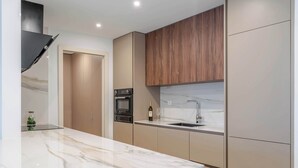 A modern kitchen with a marble countertop, built-in oven, and wooden cabinets. - Luxury Living w/ Rooftop Pool & Garage by HostWise (Vila Nova de Gaia)