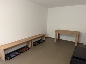 Una habitación con un banco de madera, una mesita y un mueble con cajones.