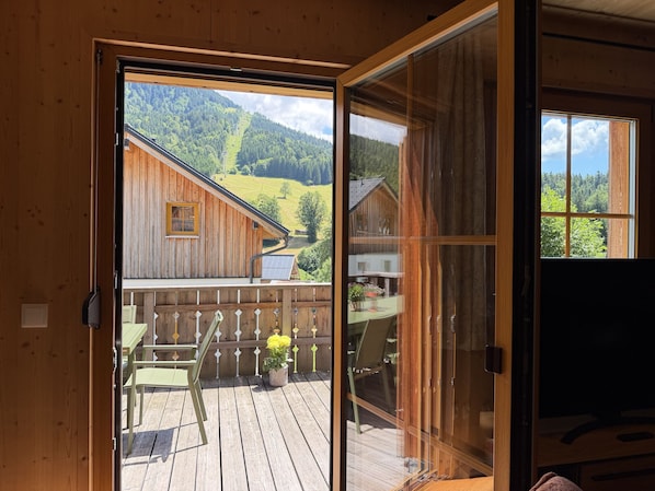 A wooden cabin with a sliding glass door leading to an outdoor deck with a table and chairs.
